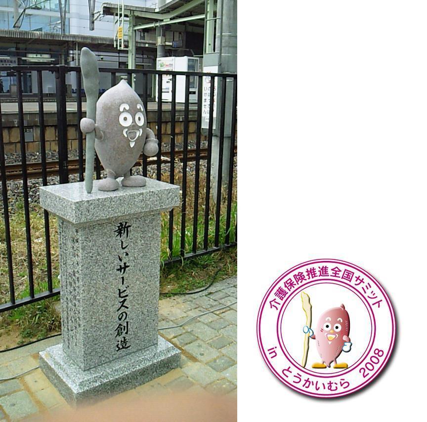 「新しいサービスの創造」と書かれた、東海村キャラクターいもジィの石像と、「介護保険推進全国サミットinとうかいむら2008」と書かれた、いもジィの丸いステッカーの写真