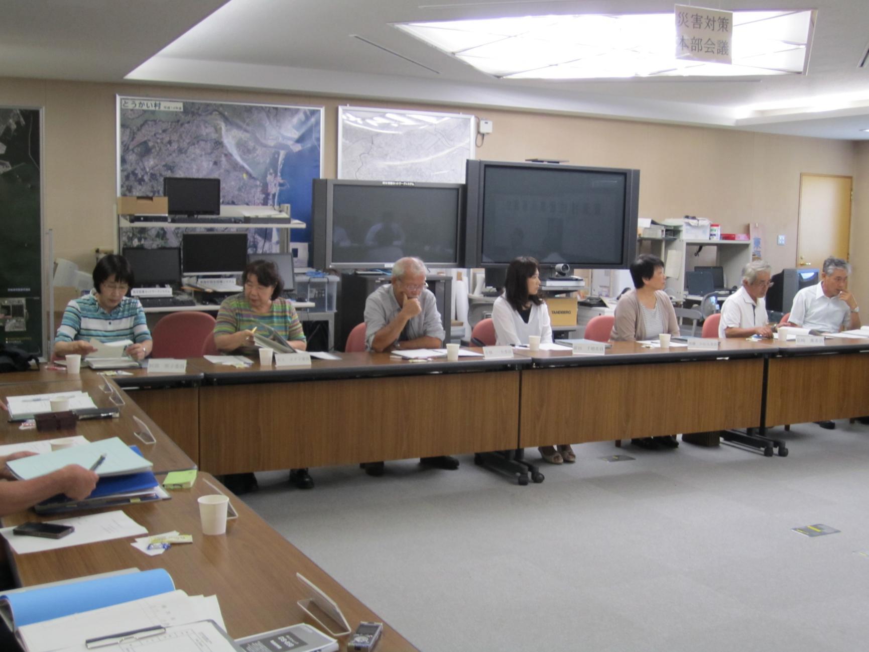 東海村住居表示審議会において、会議室にロの字型に並べられた机に向かって会議を進める参加者のうち、横一列の7名が写っている写真