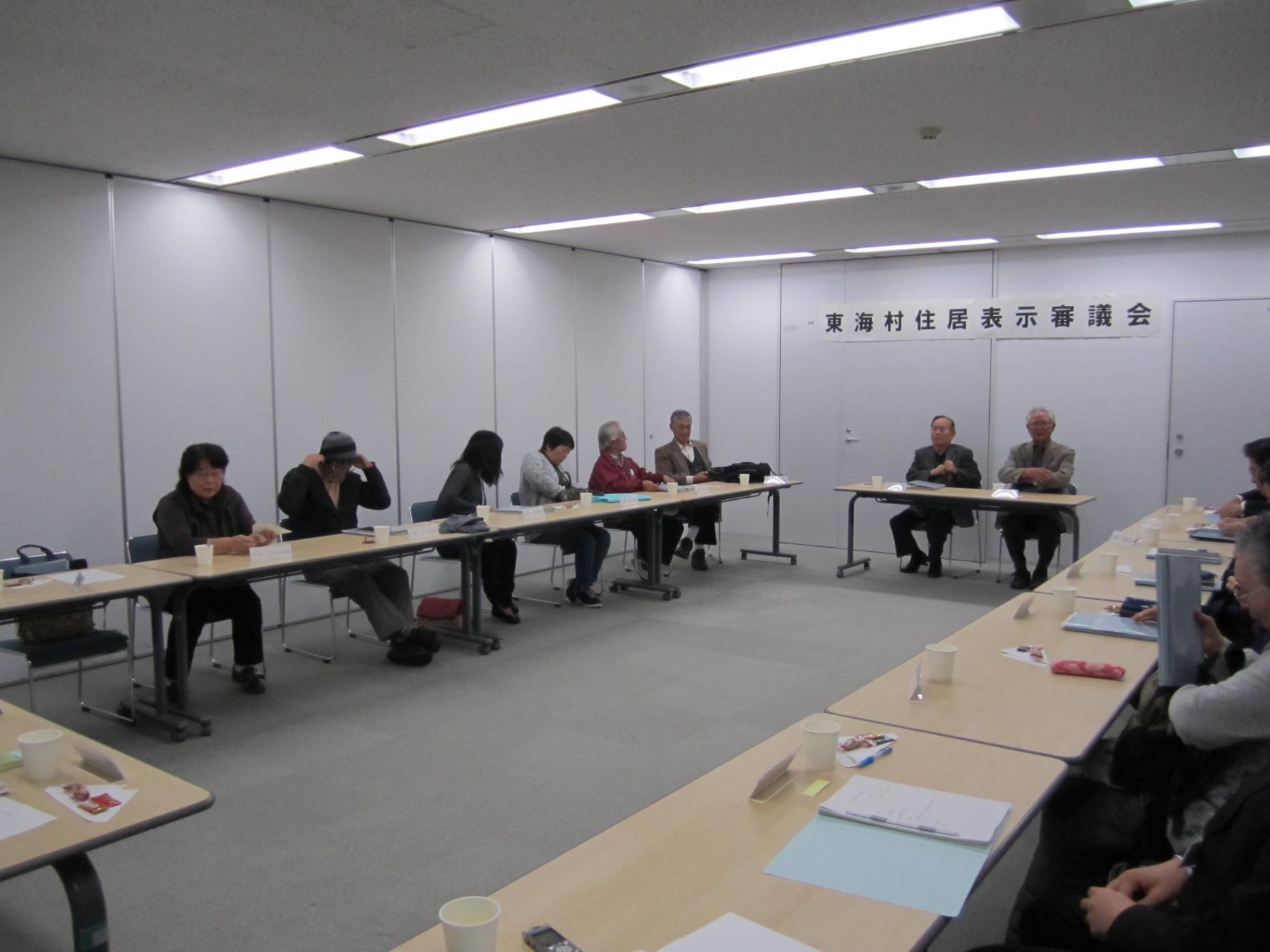 東海村住居表示審議会において、会議室にロの字型に並べられた机に向かって会議を進める参加者、12名ほどが写っている写真