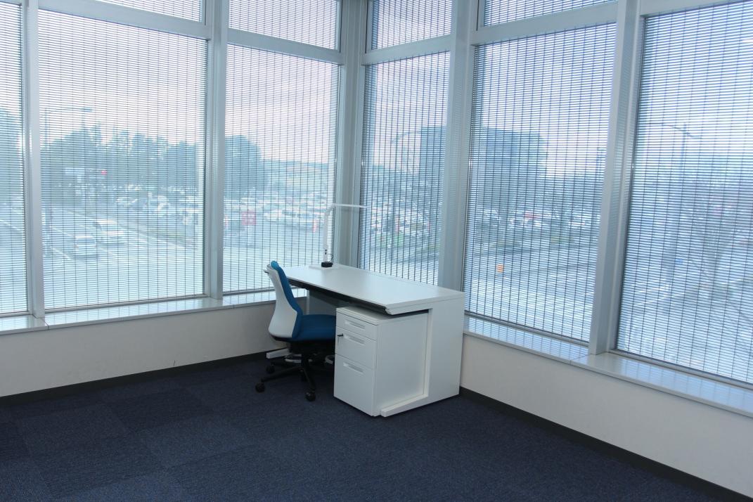 創業オフィス内、窓際に配置された白いデスクの写真