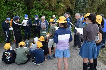 先生の説明を聞く地域の方々と小学生たち