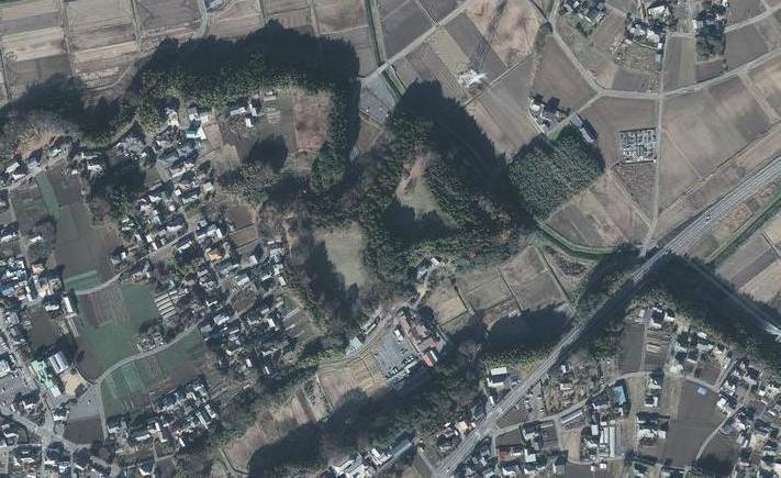 畑や家々、木々などが見える石神城跡を上空から撮影した航空写真