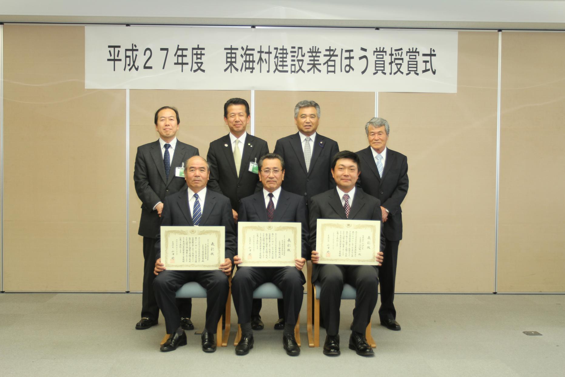 東海村建設業者ほう賞授賞式で前列にスーツ姿の男性3人が賞状を持って座り、後列にスーツ姿の男性が4人並んで立っている集合写真