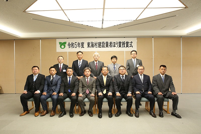 スーツを着た男性が前列に8名,2列目に5名並んだ姿の東海村建設業者ほう賞授賞式の記念写真