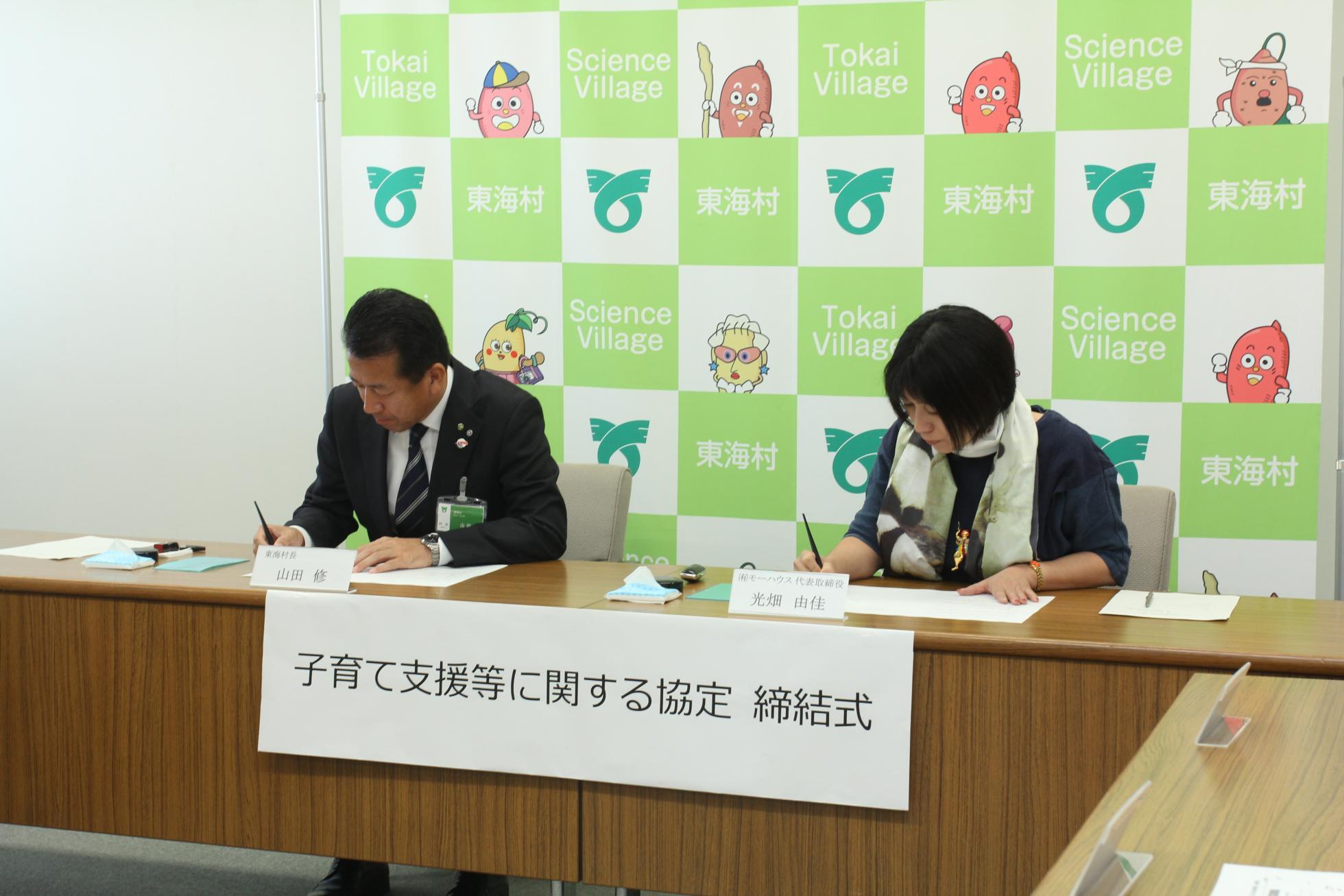 東海村村長と有限会社モーハウスの代表が署名捺印を行っている写真