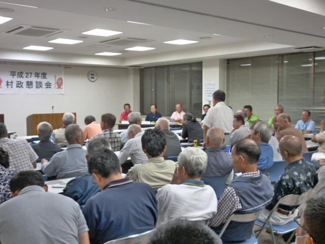 中丸地区村政懇談会で、席を立ちマイクを持って話す男性と会議室に並んだ椅子に座り話を聞いている参加者たちの写真