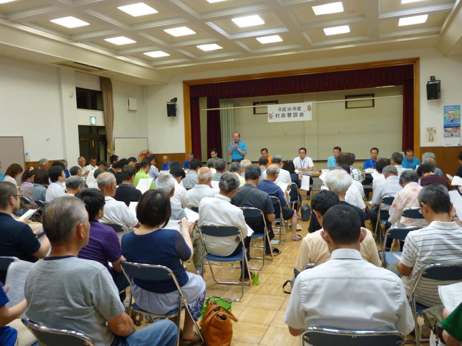 舟石川コミュニティセンターで行われた懇談会で、前方でマイクを持って話をしている男性と、着席し話を聞いている参加者たちの後方からの写真