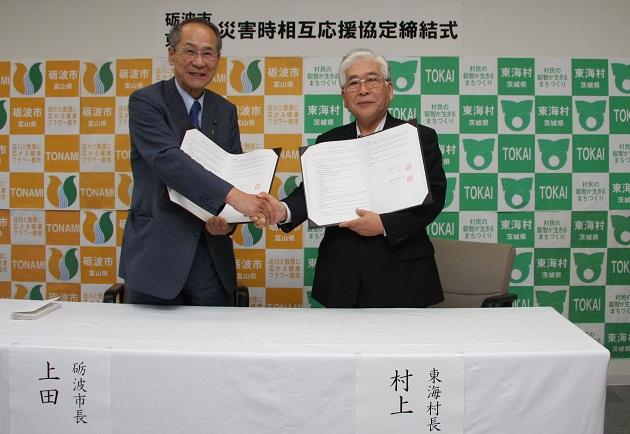 調印書を持ち握手を交わす上田砺波市長と村上東海村長の写真