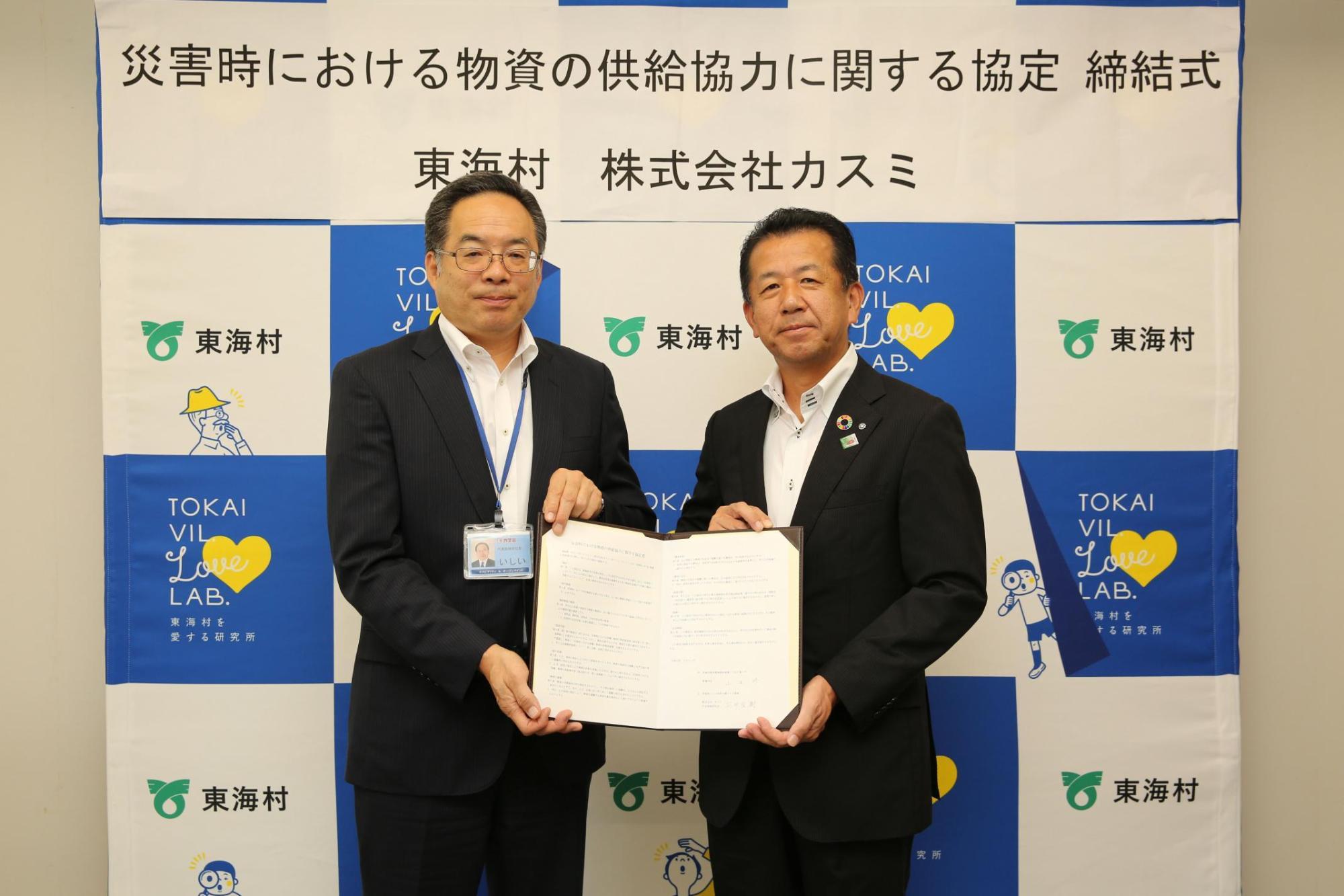 調印書を一緒に持って立っている石井社長と山田東海村長の写真